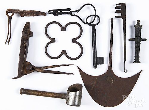 Iron implements, together with a painted miniature cannon, a metal tea scoop, and an African iron
