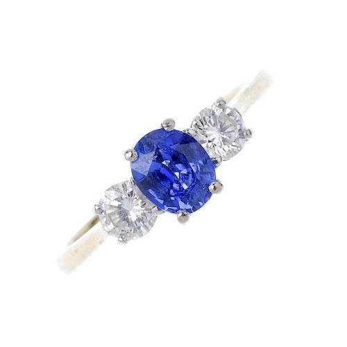 An 18ct gold sapphire and diamond three-stone ring. The oval-shape sapphire, to the brilliant-cut di