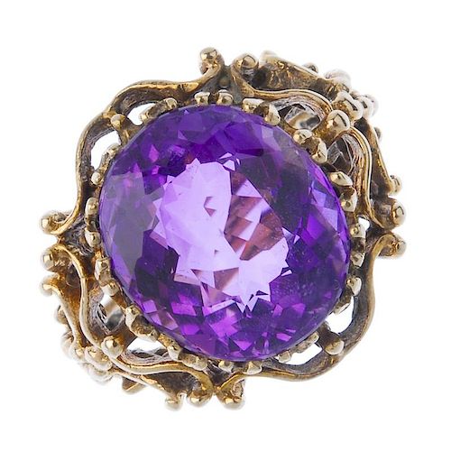 A 9ct gold amethyst single-stone ring. The oval-shape amethyst, within a bead and scroll gallery, to