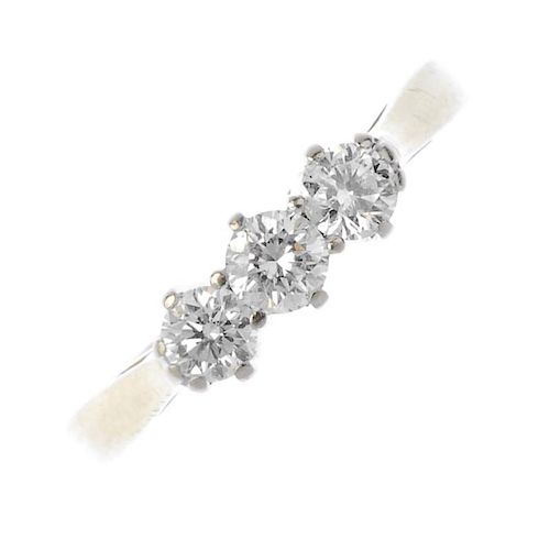 An 18ct gold diamond three-stone ring. The brilliant-cut diamond line, to the tapered shoulders and