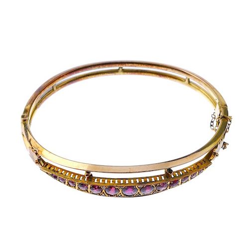 A late 19th century gold garnet hinged bangle. The front designed as a series of graduated circular-