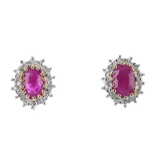 A pair of 9ct gold ruby and diamond ear studs. Each designed as an oval-shape ruby, within a single-