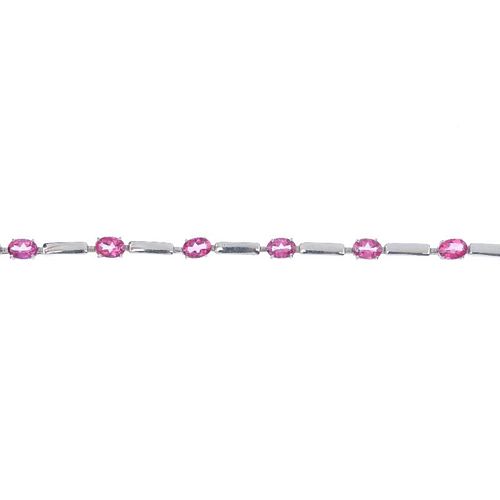 A 9ct gold topaz bracelet. Designed as an alternating series of oval-shape coated pink topaz and pol