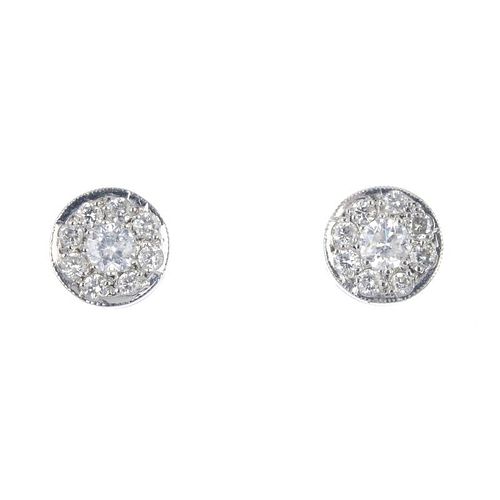 A pair of diamond cluster ear studs. Each designed as a brilliant-cut diamond cluster, within a mill