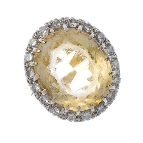 A citrine and diamond cluster ring. The oval-shape citrine, within a brilliant-cut diamond surround,