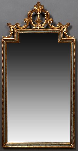 Florentine Gilt and Gesso Cushion Mirror, 19th c., with a pierced circular leaf and scroll surmount, over an architectural mirror plate flanked by nar