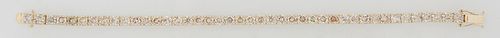 14K Yellow Gold Tennis Bracelet, each of the forty-two links with a prong set round white or pale yellow diamond, total diamond wt.- 9.9 cts., L.- 7 i