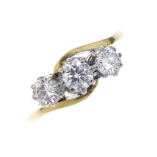 An 18ct gold diamond three-stone ring. The graduated brilliant-cut diamond diagonal line, to the cro