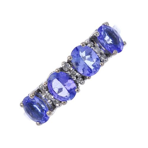 An 18ct gold tanzanite and diamond ring. The oval-shape tanzanite line, interspaced by single-cut di