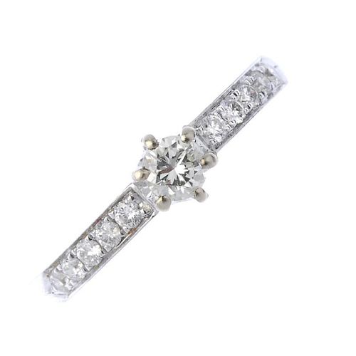 A diamond single-stone ring. The brilliant-cut diamond, with similarly-cut diamond line sides, to th