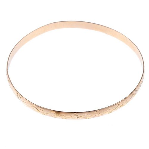 Three slave bangles. To include two 9ct gold textured bangles, together with a floral engraved bangl