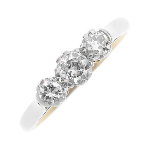 A mid 20th century gold and platinum diamond three-stone ring. The brilliant-cut diamonds, to the ta