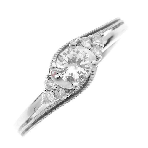 A 9ct gold diamond crossover ring. The brilliant-cut diamond, with similarly-cut diamond trefoil sid