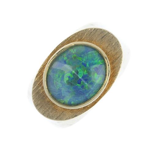 An opal triplet ring. The oval opal triplet, within a textured surround, to the tapered shoulders. W