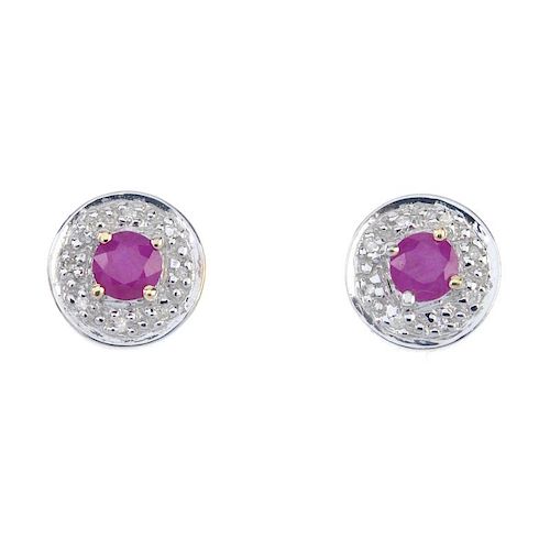 A pair of 9ct gold ruby and diamond ear studs. The circular-shape ruby, within an illusion-set diamo