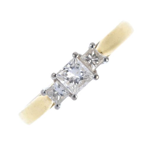 An 18ct gold diamond three-stone ring. The graduated square-shape diamond line, to the tapered shoul