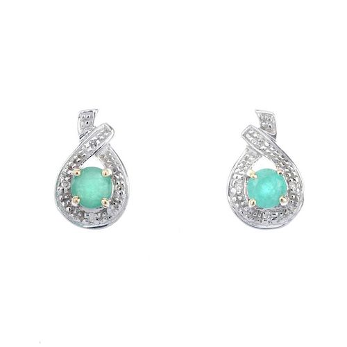 A pair of emerald and diamond earrings. Each designed as a circular-shape emerald, within an illusio
