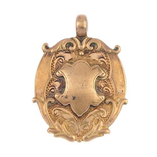 An early 20th century 9ct gold medallion. The shield-shape panel, raised within a scrolling surmount