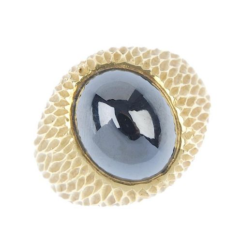 A hematite ring. The oval hematite cabochon, inset to the textured surround and plain half-band. Wei