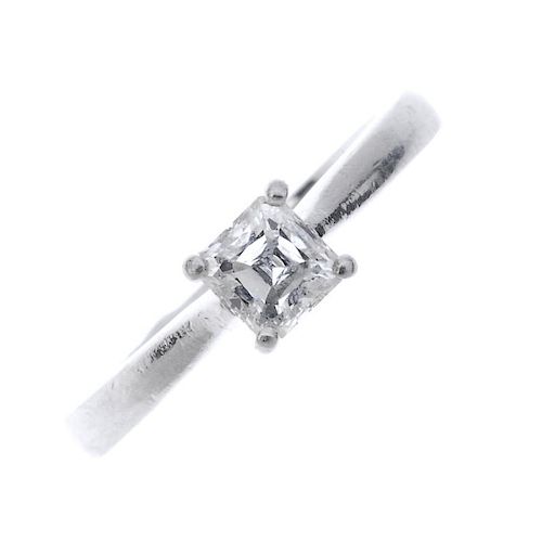 A platinum diamond single-stone ring. The square-shape diamond, to the tapered shoulders and plain b