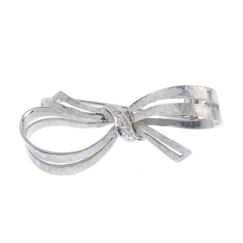A 1980s 18ct gold diamond bow brooch. The single-cut diamond line to the textured bow. Import marks