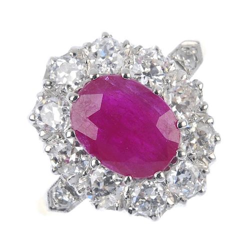 A ruby and diamond cluster ring. The oval-shape ruby, within an old-cut diamond surround, to the sim