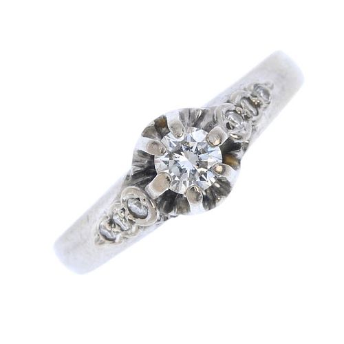 A diamond single-stone ring. The brilliant-cut diamond, to the similarly-cut diamond line shoulders