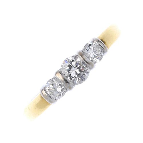 An 18ct gold diamond three-stone ring. The slightly graduated brilliant-cut diamond line, with bar s