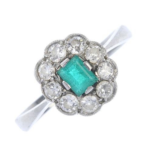 A mid 20th century platinum emerald and diamond cluster ring. The rectangular-shape emerald, within