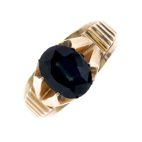 A gentleman's 9ct gold sapphire signet ring. The oval-shape sapphire, to the grooved sides and taper