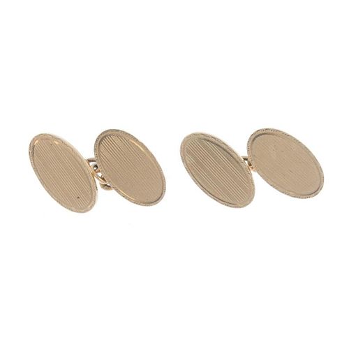 A pair of 9ct gold cufflinks. Each designed as two oval-shape panels, with engine-turned design, to