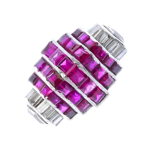 (546079-2-A) A 1940s ruby and diamond cocktail ring. The calibre-set ruby stepped chevron panel, wit