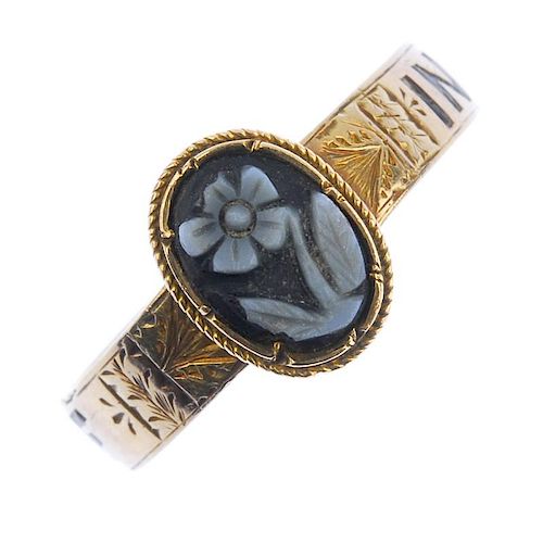 A mid Victorian gold memorial ring. The central oval onyx panel carved to depict a forget-me-not to
