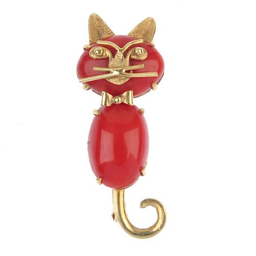 A coral cat brooch. Designed as a cat with bow-tie, comprising two oval coral cabochons, to the face