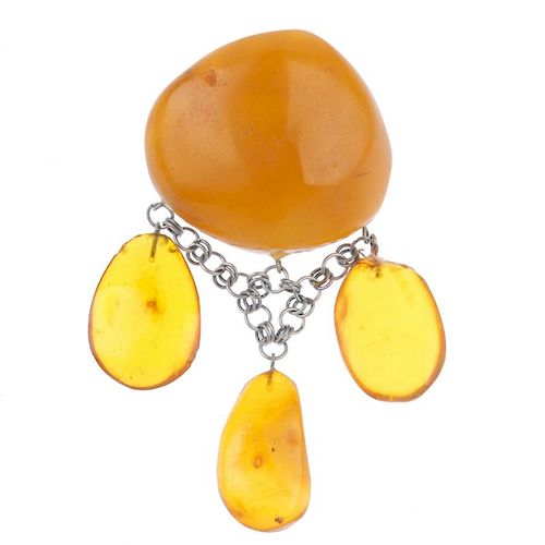 A natural amber brooch. The irregular-shape translucent polished amber panel, suspending three oval-