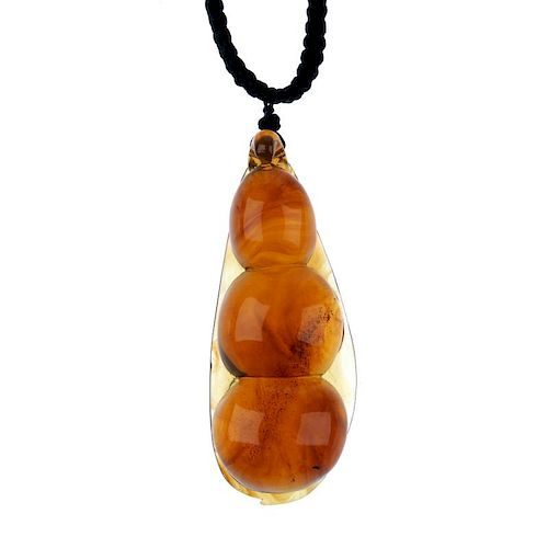 A natural Burmese amber pendant carved as a pea pod. The plaited black cord suspending the pear-shap