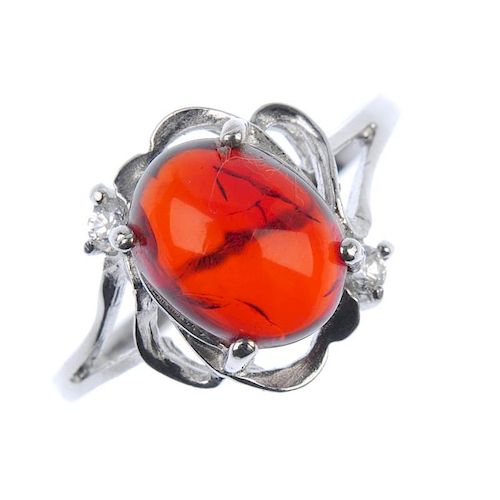A natural Burmese blood amber ring. The blood amber cabochon, measuring 0.7cms, to the scrolling sur