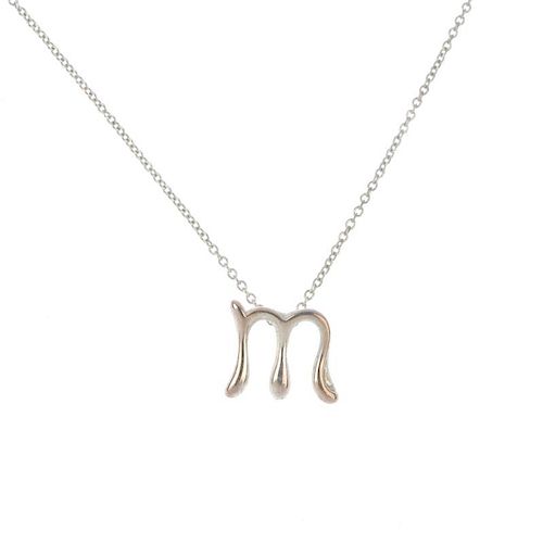 TIFFANY & CO. - an Elsa Peretti initial pendant. Designed as the letter 'M', suspended from a trace-