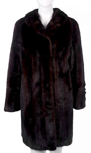 A knee-length ranch mink coat. Featuring a notched lapel collar, hook and eye clip fastenings and tw