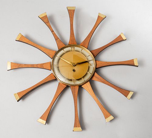 Reloj de pared. Francia, SXX. Elaborado en madera y metal dorado. Diseño solar. Mecanismo de cuerda. Carátula circular. 52 cm diámetro.