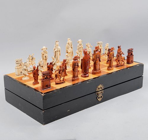 Juego de ajedrez. China, SXX. Talla en marfil acabado crudo y cinabrio. Estuche abatible de madera para tablero. 60 x 14 x 30 cm.