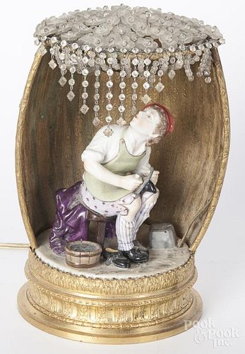 German porcelain cobbler figure, inset into a barrel formed table lamp, 20th c., with a glass flower