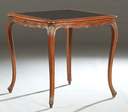 Louis XV Style Carved Mahogany Games Table, early 20th c., the stepped rounded edge bowed top with an inset gilt tooled black leather playing surface,