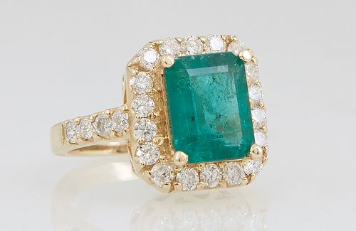 Lady's 14K Yellow Gold Dinner Ring, with a 2.97 carat emerald atop a conforming border of round diamond, the shoulders of the band also mounted with r