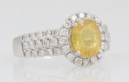 Lady's Platinum Dinner Ring, with a 2.01 carat oval yellow sapphire atop a border of round diamonds, the shoulders of the tapering band with five rows