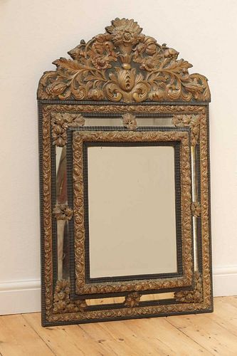 An ebonised and embossed brass wall mirror,