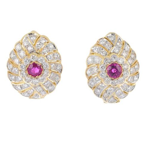 A pair of ruby and diamond earrings. Each of openwork design, the circular-shape ruby, to the brilli