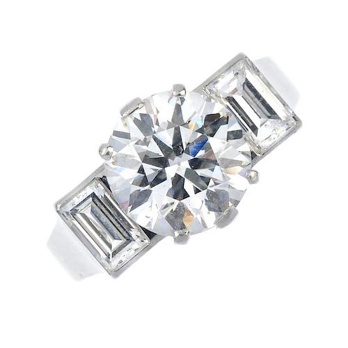 A diamond three-stone ring. The brilliant-cut diamond, weighing 3.04cts, to the rectangular-shape di