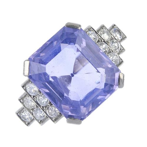 A sapphire and diamond dress ring. The rectangular-shape violet sapphire, to the brilliant-cut diamo