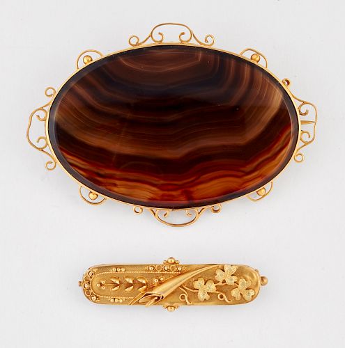 A VICTORIAN BANDED AGATE BROOCH, an oval brown agate within a fancy scroll 